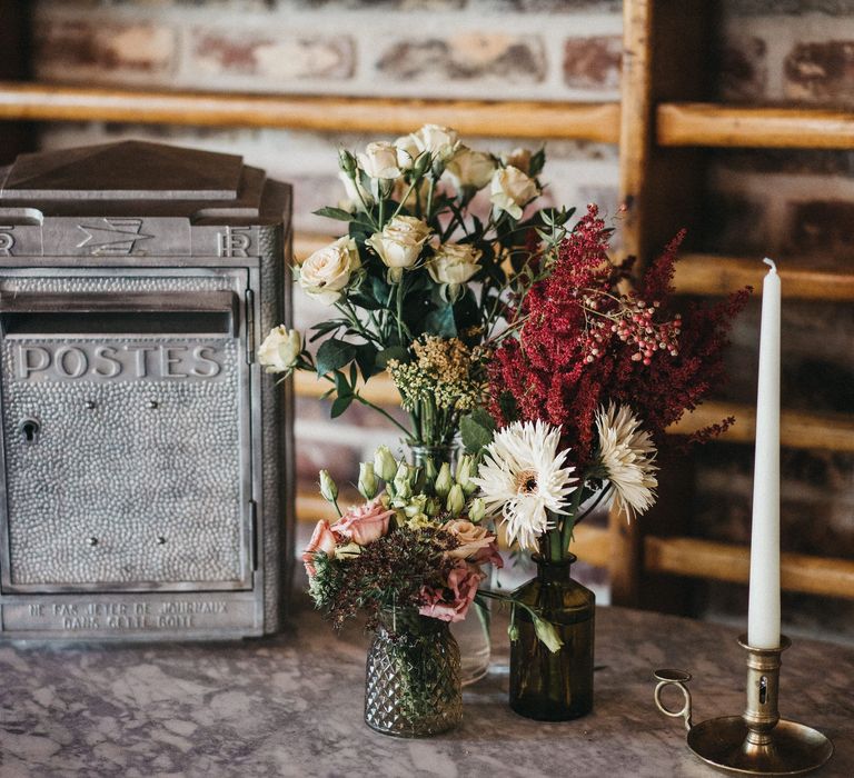 Wedding flowers in different vessels and silver postbox for wedding cards