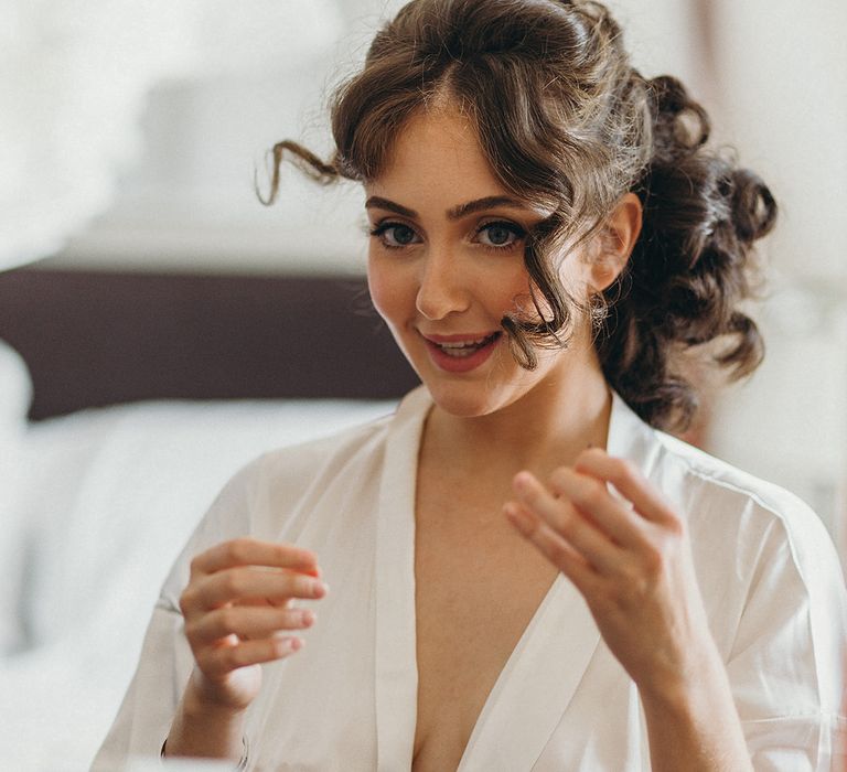 Bride in a white getting ready robe with curly hair 