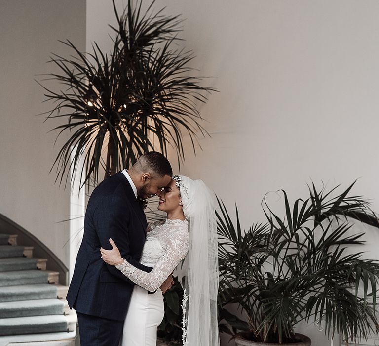 A muslim couple embrace at the foot of some stairs at their wedding.