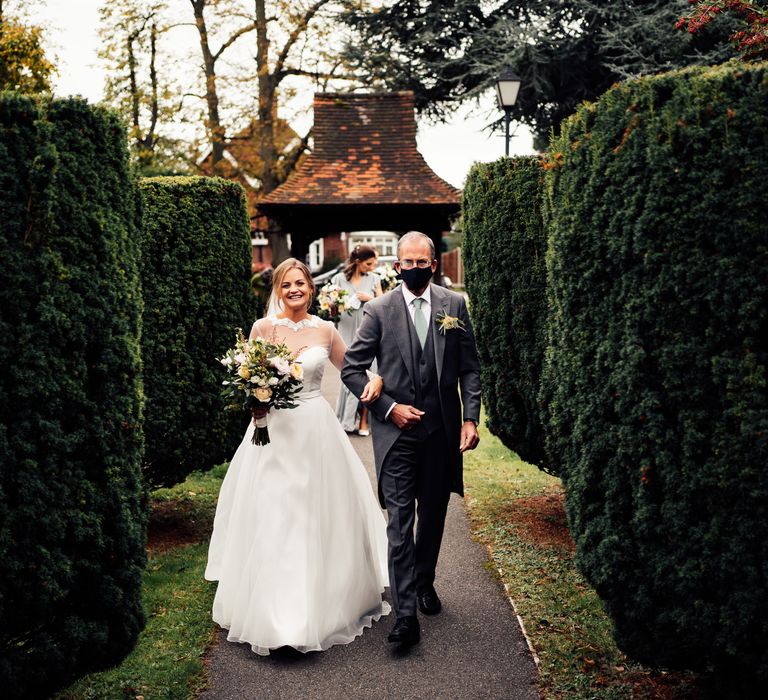 Bride walks through grounds with father on wedding day 