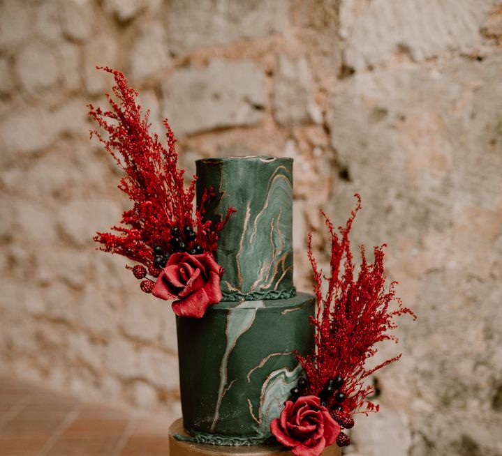 Green and gold gothic wedding cake with marble tier and red flowers decor 