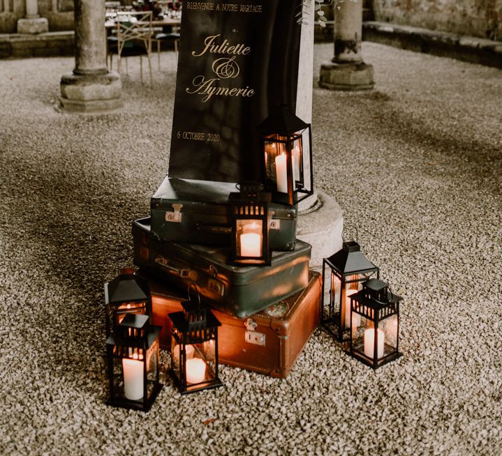 Vintage suitcases, lanterns and black and gold wedding welcome sign 