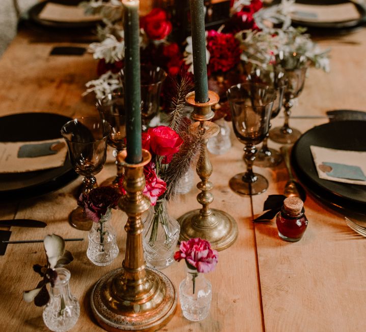 Gothic style wedding table decor with black tableware, red flowers and candlelight