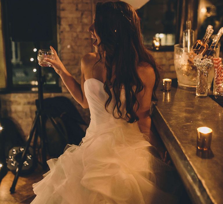 Bride celebrating sat at the bar at her wedding - Olympic studios Barnes 