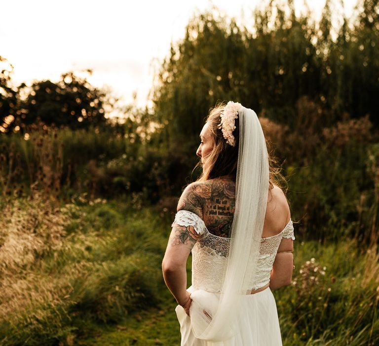 Bride walks through the garden whilst wearing floor-length veil 