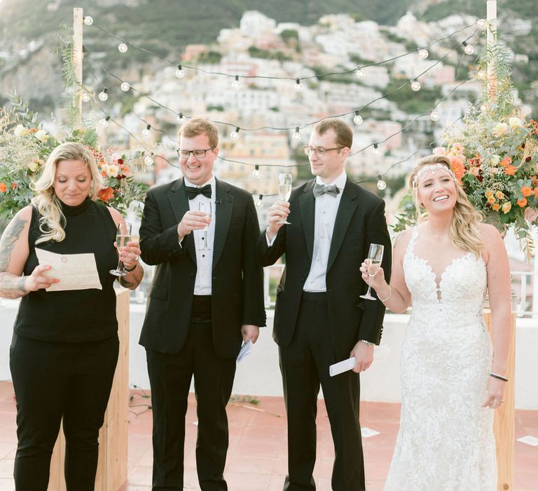 The brides, and two ceremony officiants all raising at toast at the end of the wedding ceremony