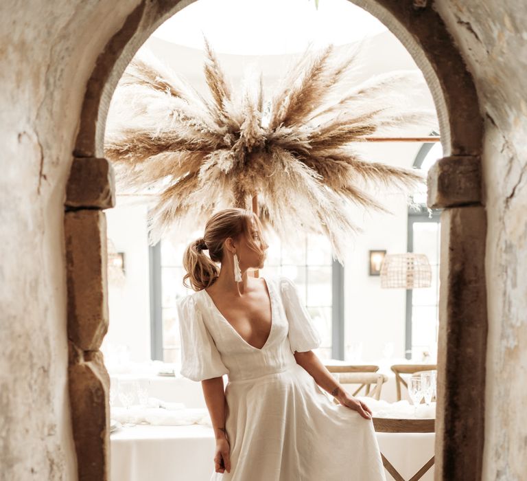 Bride in a linen wedding dress with blouson sleeves and plunging neckline 