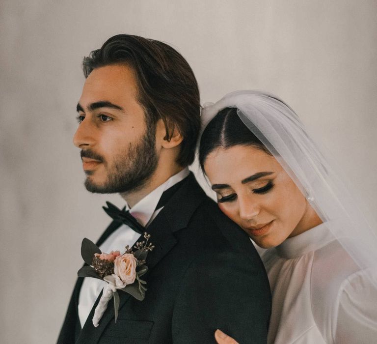 Bride leans into the back of groom on the day of her wedding