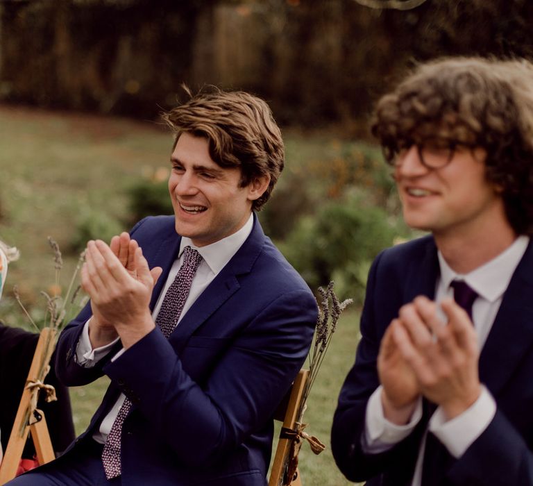 Smiling wedding guests clap the bride and groom at garden party wedding at Hayne, Devon