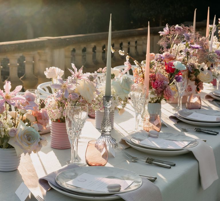 Sun pours over luxury tablescape with pastel florals and white candles on white table cloth