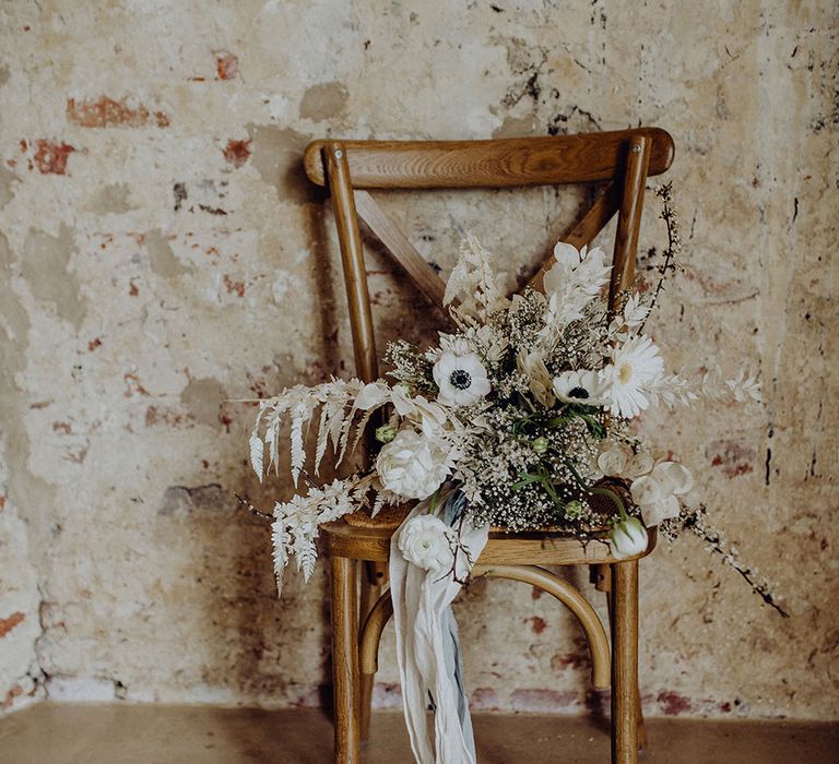 White flower wedding bouquet resting on a wooden chair 