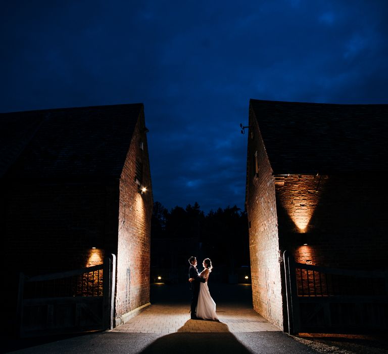 Bride & groom embrace outdoors during the night