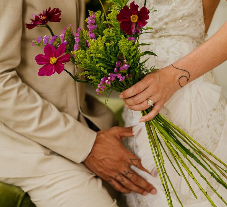 Bride wearing a diamond a yellow gemstone engagement ring holding a wildflower bouquet 