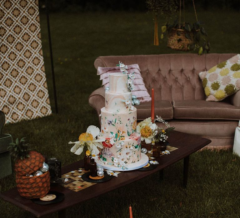 Marble wedding cake with wildflower illustration resting on a retro coffee table 