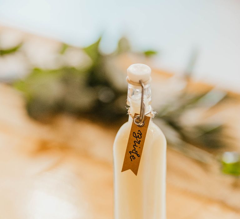 Homemade limoncello in glass bottle complete with brown name tag on wooden table