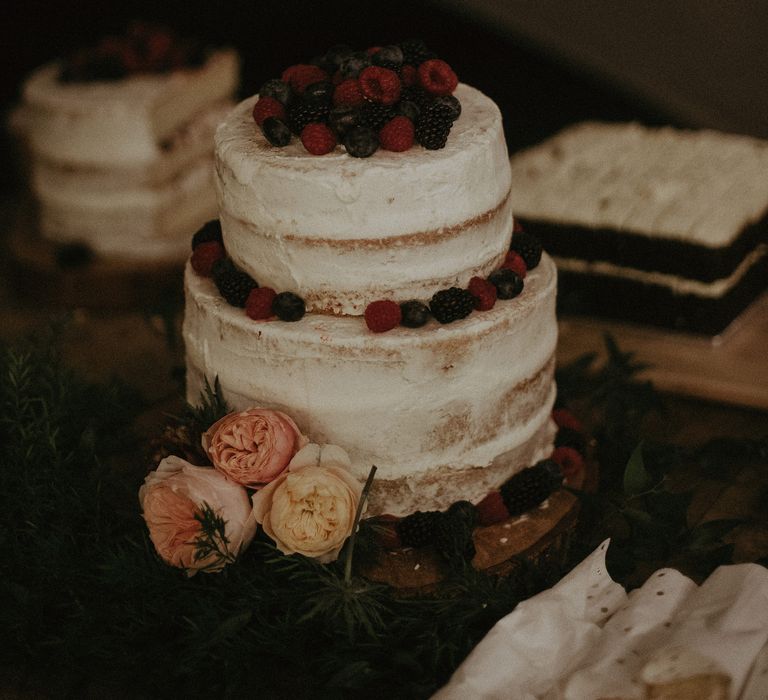 2-tier naked wedding cake with white frosting and berries 