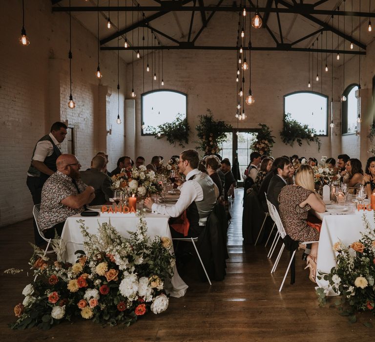 Wedding guests sitting at the peach decorated Osea Island wedding reception 