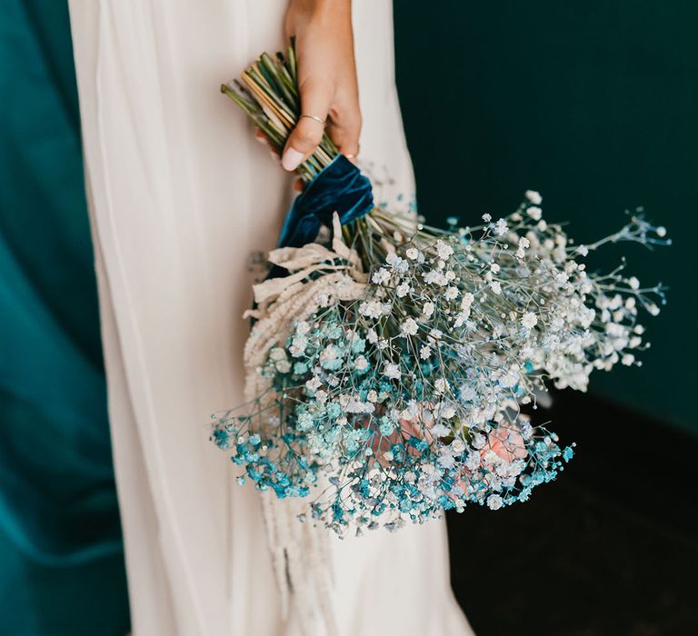 Bride with white wedding nails holding her white and teal gypsophila bouquet down by her side 