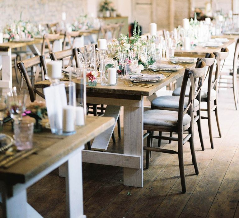 rustic romance wedding decor with clear glass charger plates, pink flowers, foliage and festoon lights on wooden tables