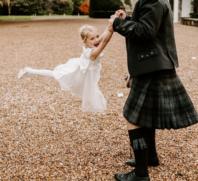 Wedding guest in a kilt and sporran swinging the flower girl around