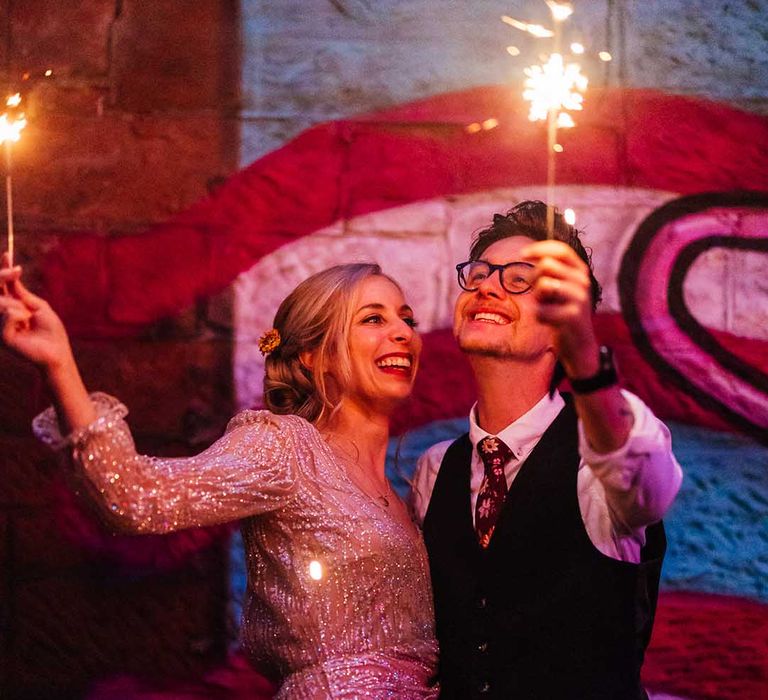 Bride & groom lift sparklers in the air on their wedding day