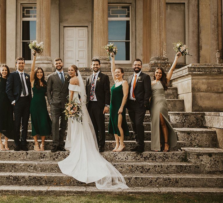 Bride & groom celebrate with their wedding party on the staircase of wedding venue outdoors 