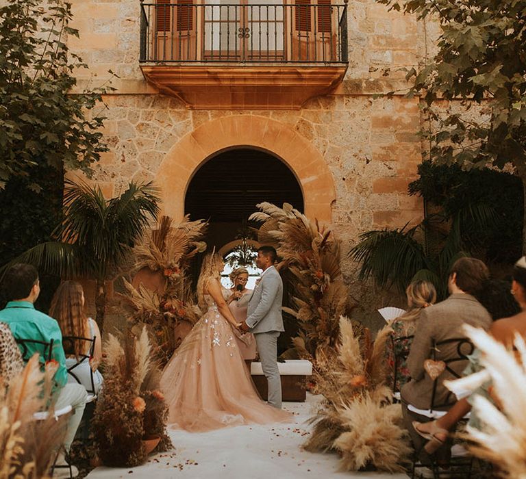 Bride & groom stand holding hands for outdoor ceremony 