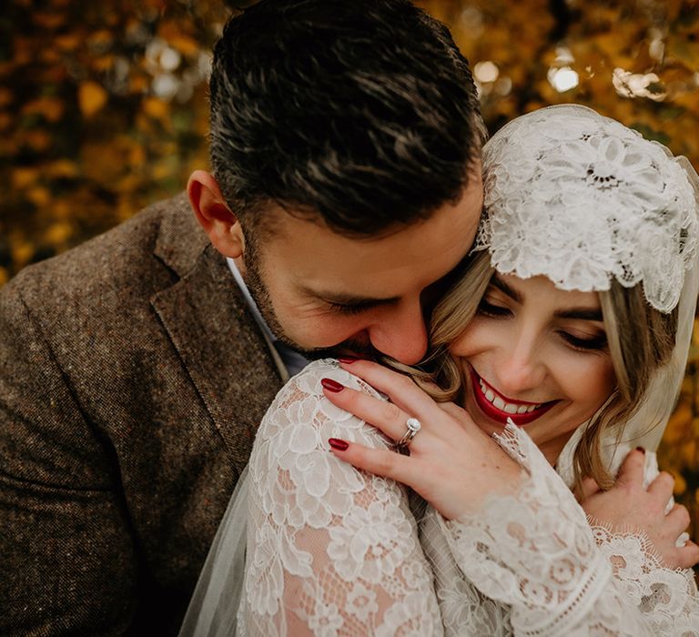 Groom nuzzling his bride's neck in a Juliet cap veil with bright red lipstick and nails 