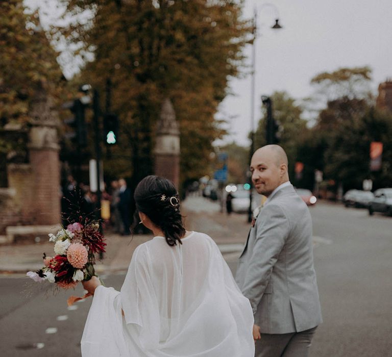 Grooms holds his brides hand as they walk with one another after wedding ceremony