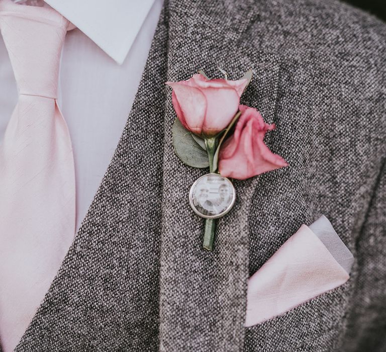 Grey tweed suit with pink rose buttonhole and personalised pin of groom and lost family member 