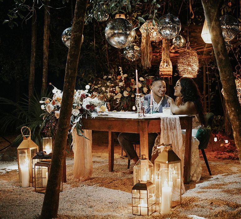 Bride and groom on private top table with candle lanterns and disco balls overhead 