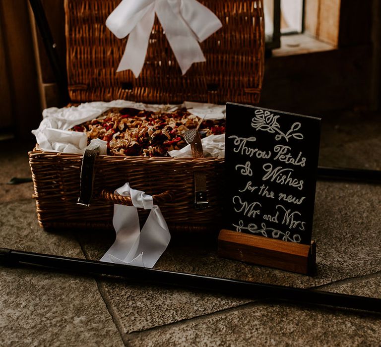 Chalk board sign with rhyme to signify the confetti in dark brown wicker basket