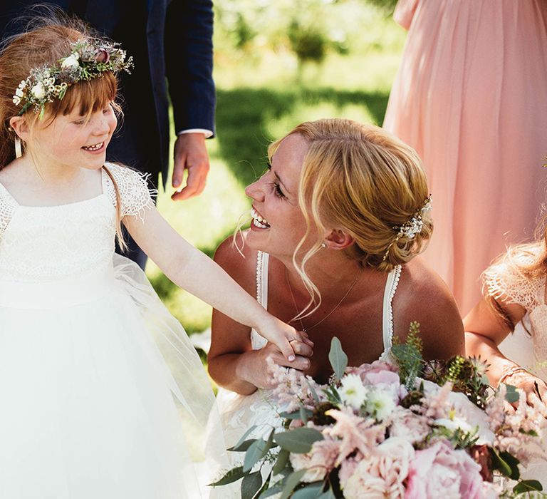 Bride speaks to flower girls in puff tulle dress with flower crown and lace cap sleeves