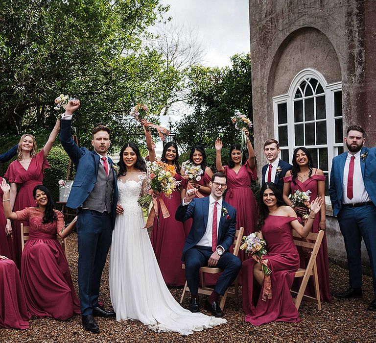 Wedding party including bridesmaids in wine bridesmaid dresses, groom and groomsmen in navy blue suits and bride in lace wedding dress 