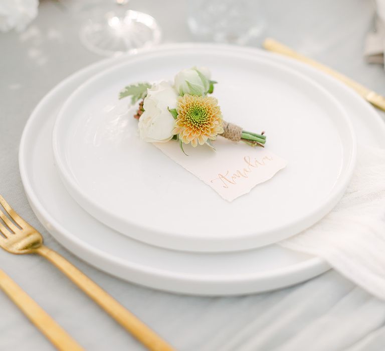 Place setting with delicate white buttonhole flower