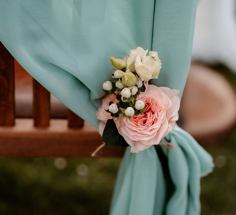 Draped blue fabric tied with pink rose wedding chair back decor 