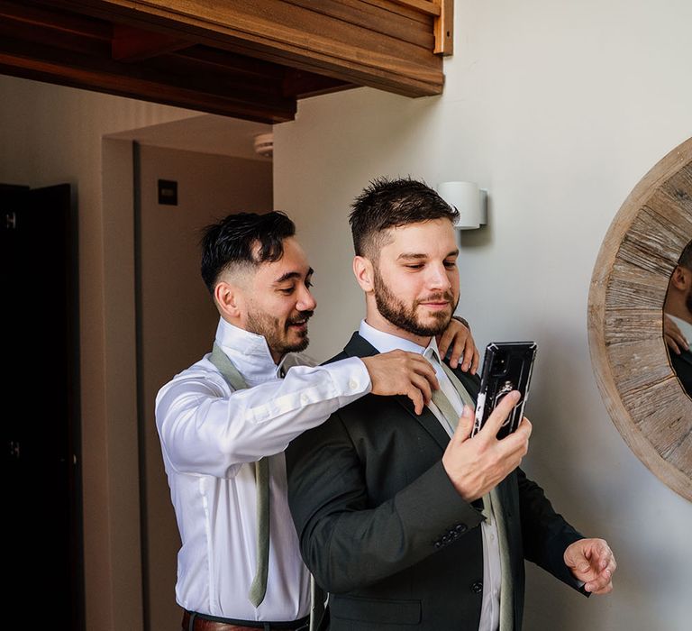 Groom & groomsmen get ready on the morning of wedding wearing matching suits and green ties with white shirts 