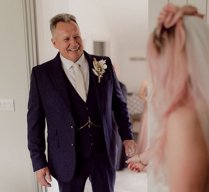 Father of the bride wearing three piece suit complete with dried floral buttonhole sees his daughter for the first time 