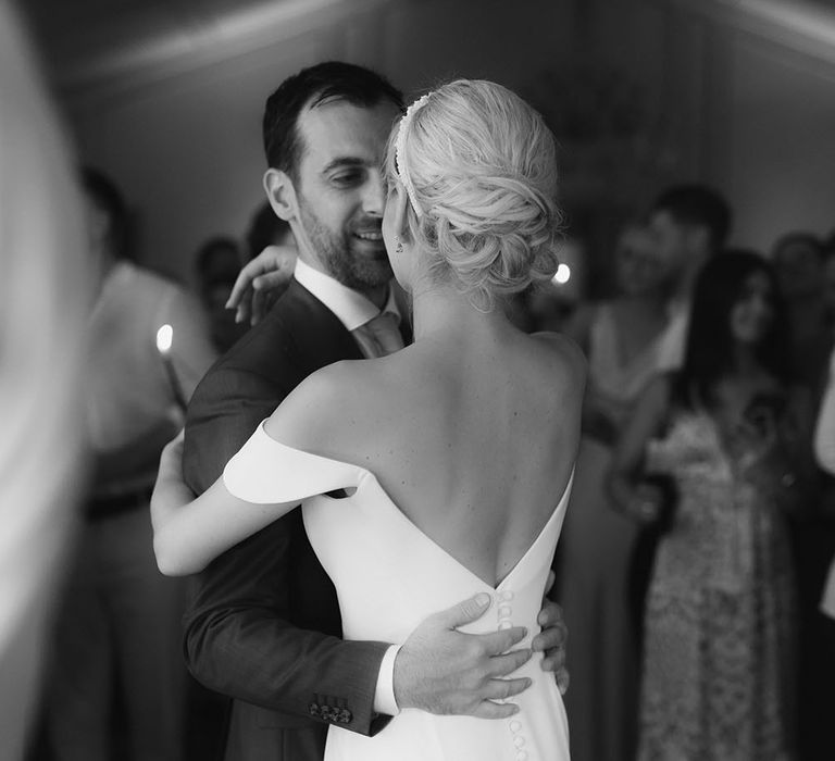 Bride wears her hair in low chignon as she dances with her groom during wedding reception 