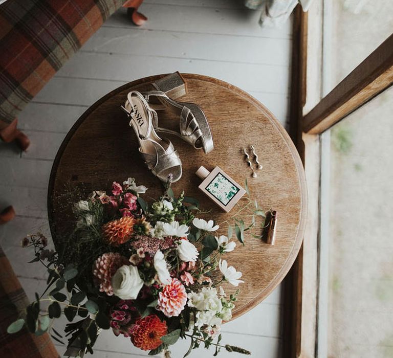 Bride's gold metallic wedding shoes with a coral and white bouquet, earrings and Gucci perfume 