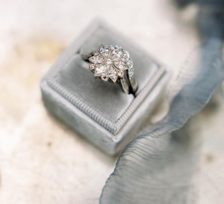 Large flower engagement ring and wedding band in a blue ring box  