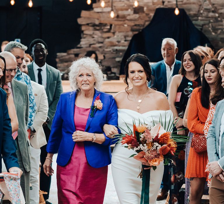 Mother of the bride in a bright pink dress and blue blazer walks the bride in her ASOS wedding dress down the aisle 