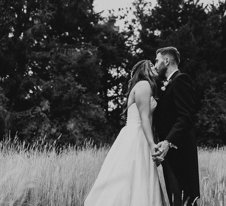 Bride and groom share a kiss while holding hands on their wedding day 