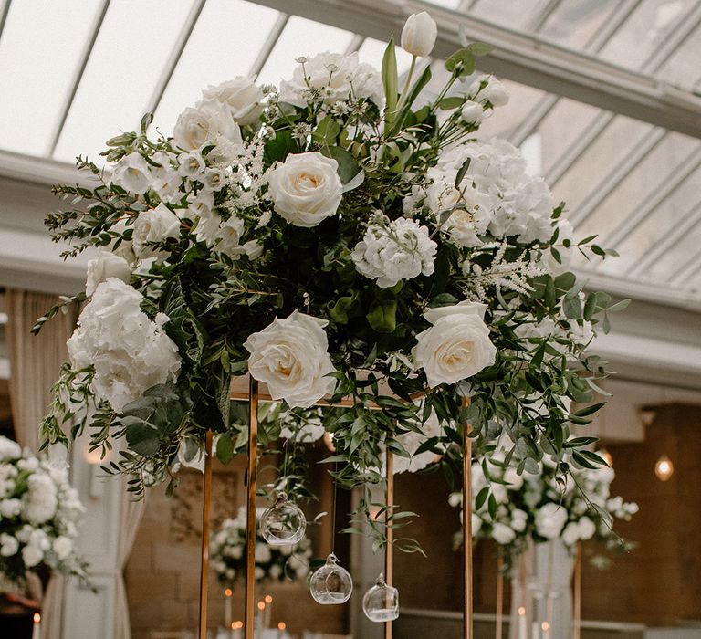 White & green flower installation centrepiece with hanging tea light candles 