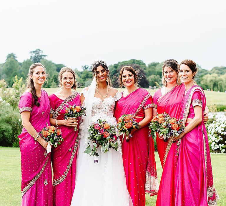 Bride with bridesmaids in bright magenta dresses and saree