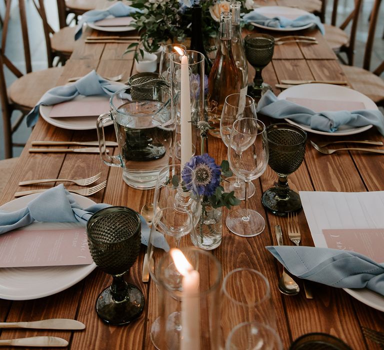 Pastel wedding flowers decorate the wedding tables with pink menus and blue napkins with coloured glassware 