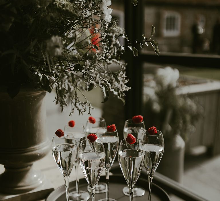 Black tray of glasses of champagne decorated with raspberries for the wedding drinks 