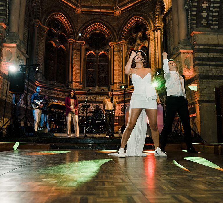 Bride in trainers and short white wedding dress dances with her groom as they recreate Napoleon Dynamite dance scene 