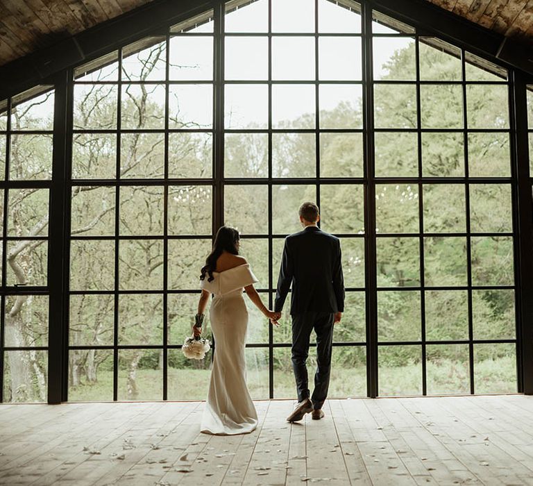 The bride and groom look out over at the view from Hidden River Cabins rustic wedding venue in the North West 