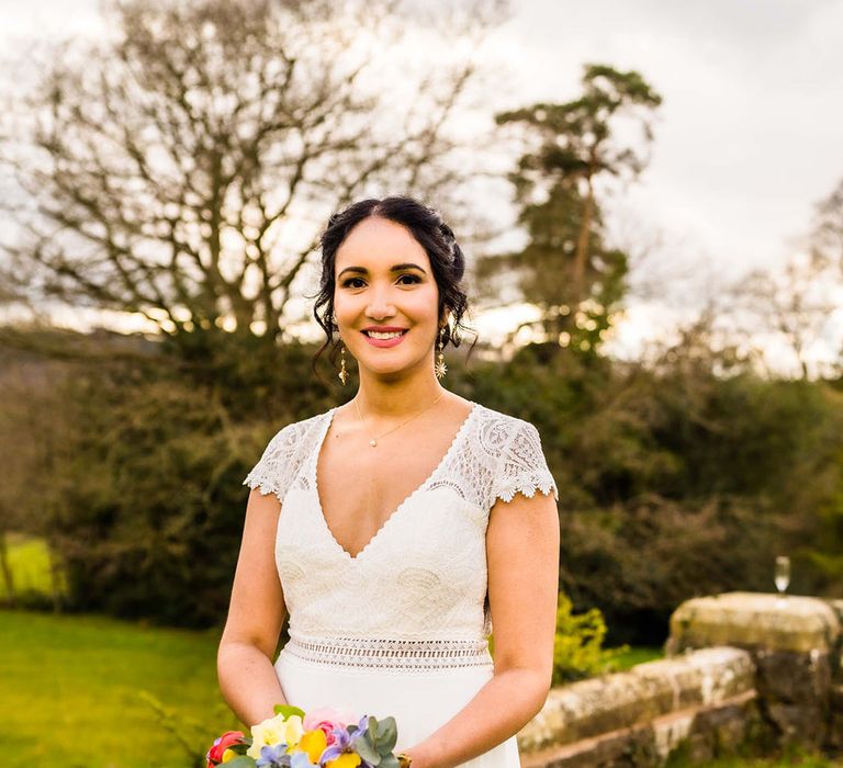 Bride holds waterfall styled bridal bouquet complete with Spring flowers in vibrant colours 